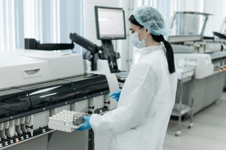 Laboratory worker in protective gear handling diagnostics equipment.